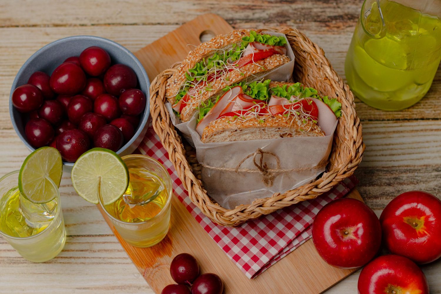 Fresh fruits and beverages arranged on a rustic wooden table with red apples and cherries.