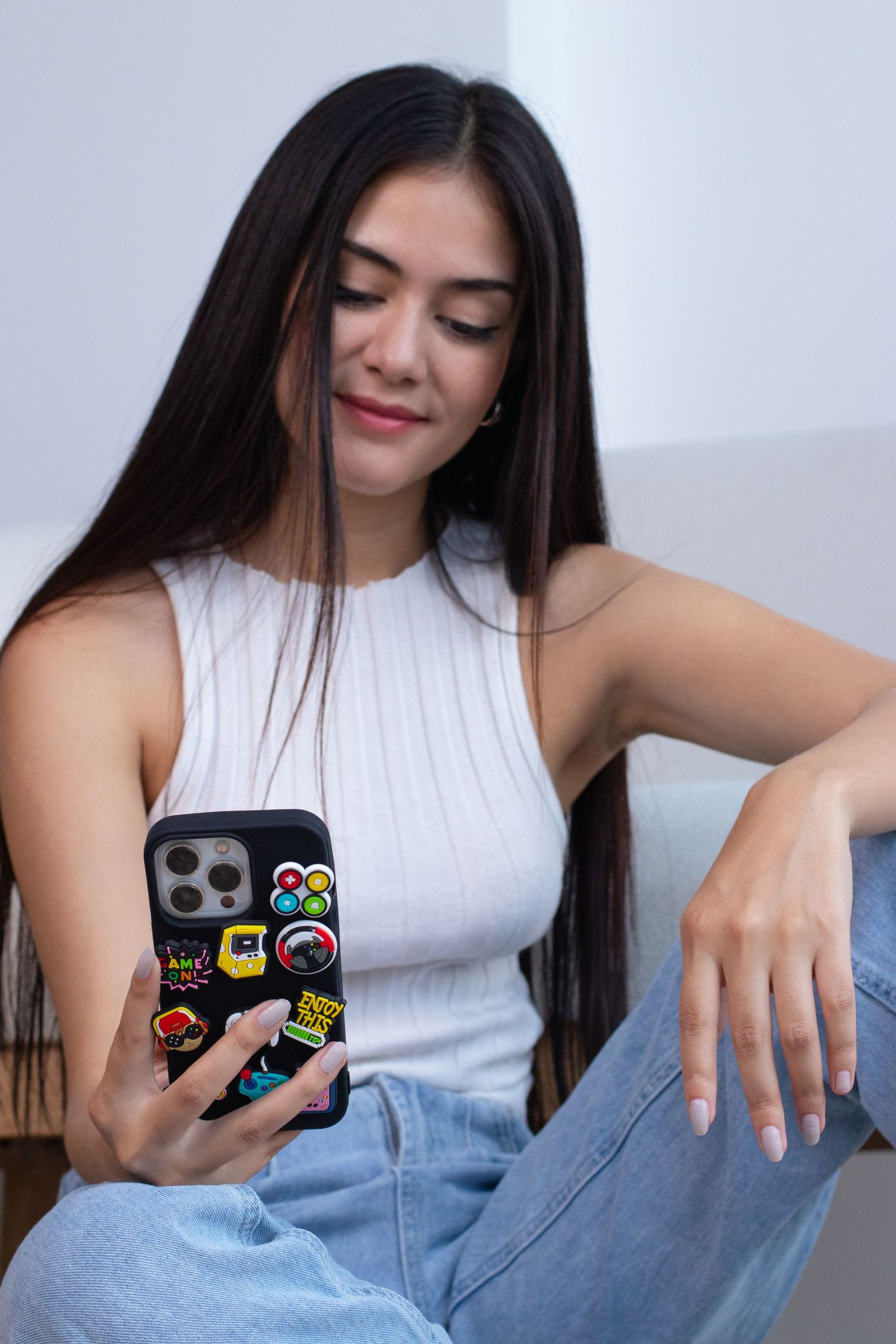 Woman in white tank top demonstrating phone case with stickers in progressive shots.