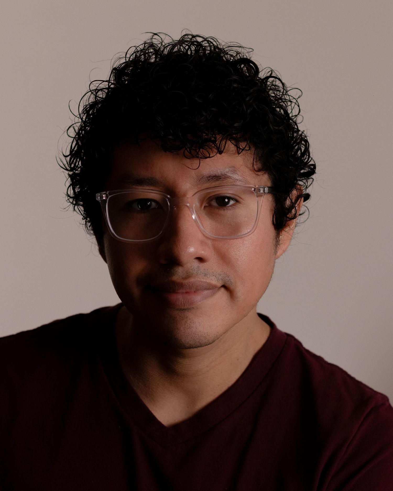 Studio portrait series showing burgundy shirt and glasses against neutral background.