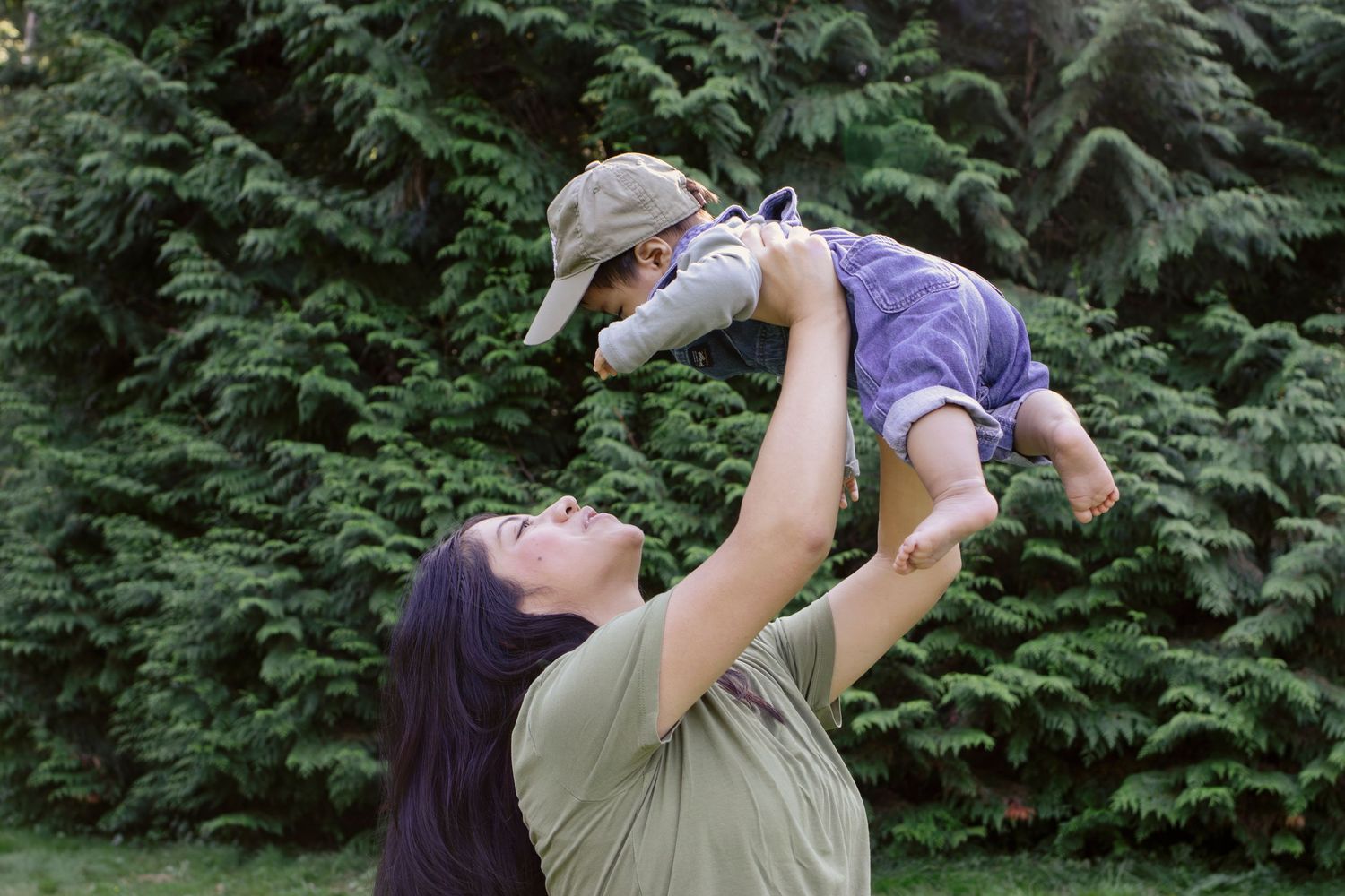 Playful outdoor moment with baby being lifted against evergreen trees.
Central Park Burnaby