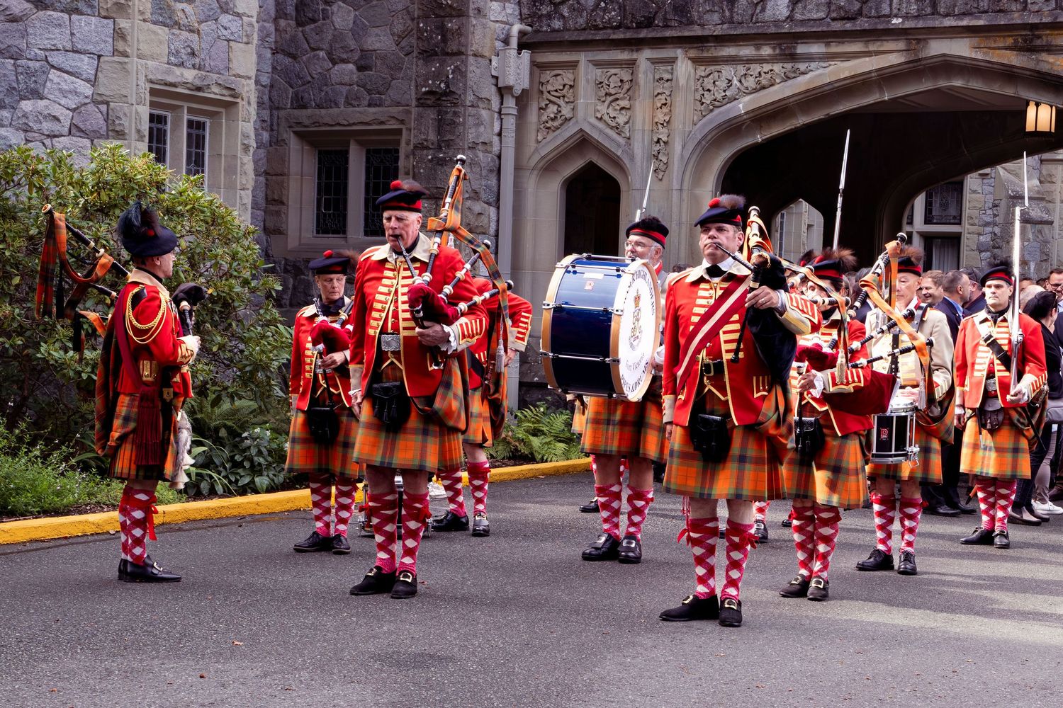 A sequence of dancers in red and white polka dot costumes performing a traditional dance routine in front of a building.