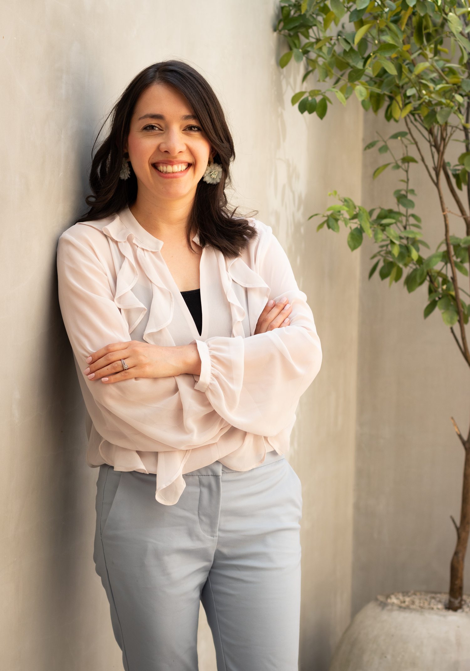 Professional headshot in light blazer with indoor plant backdrop.
