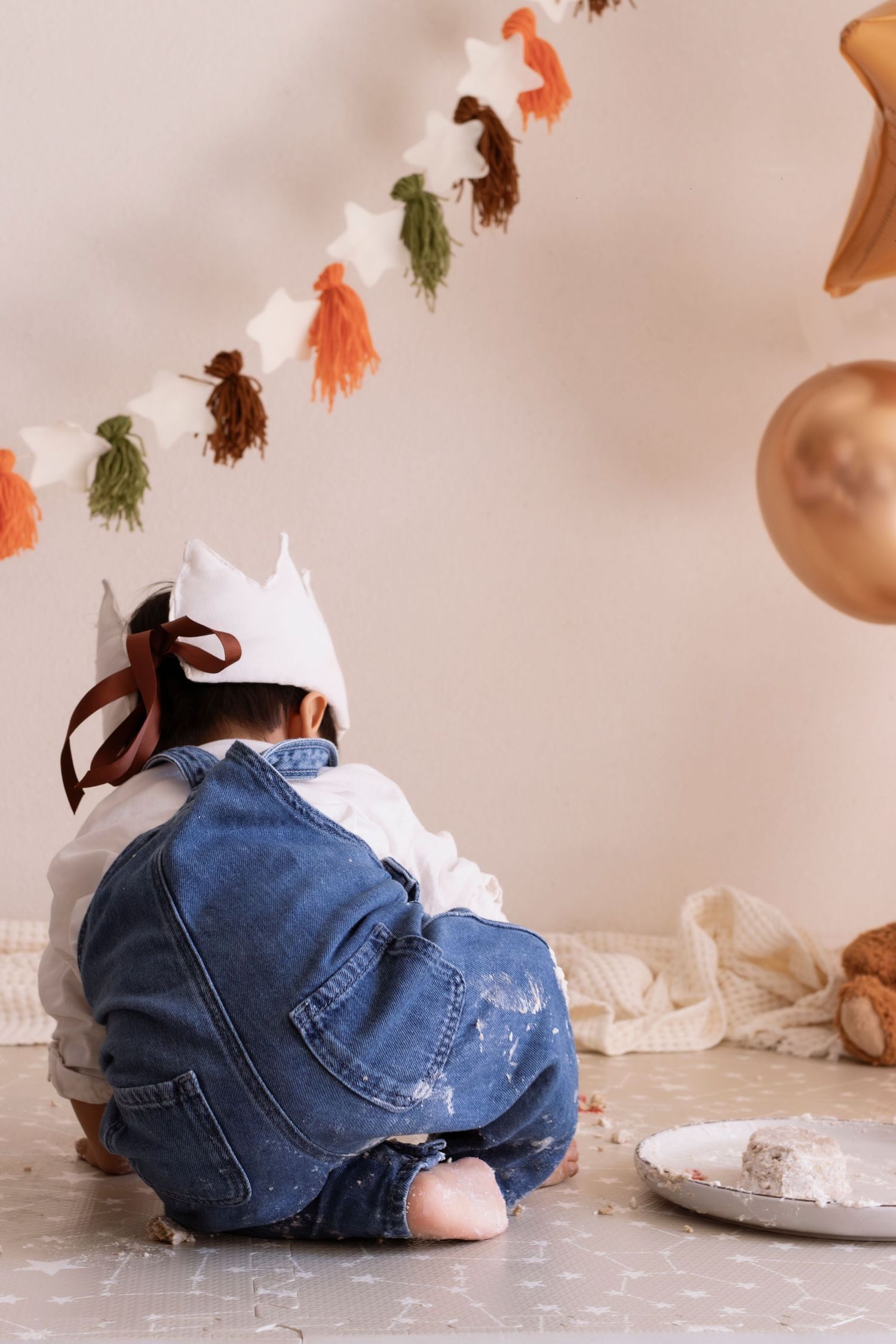 A series of photos showing a baby in denim overalls crawling and rolling on a polka dot floor with colorful decorations.
