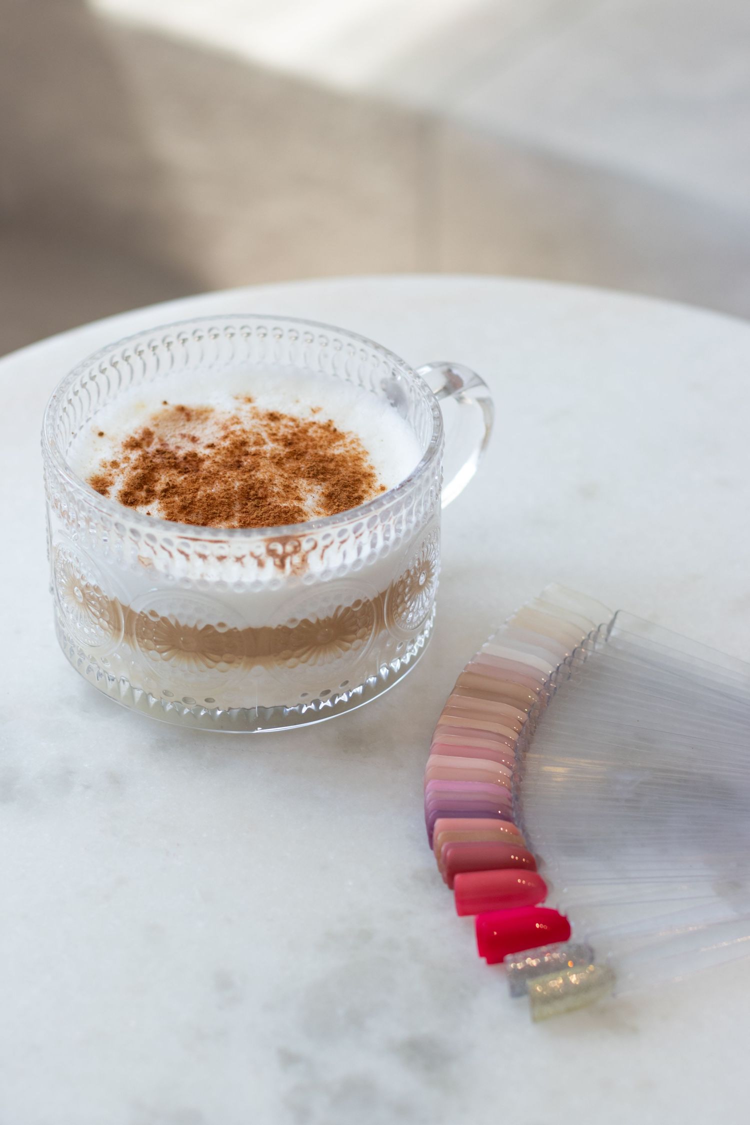 Glass dish with dusted cocoa powder and pink color swatches arranged on white marble surface.