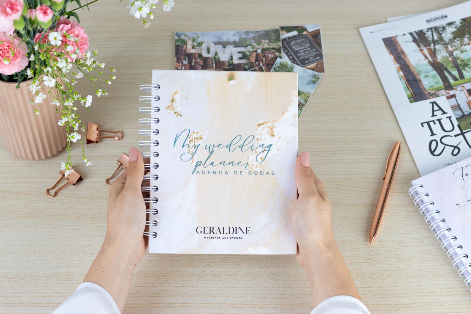 Flatlay of desk with floral decorations, notebooks and planning materials.