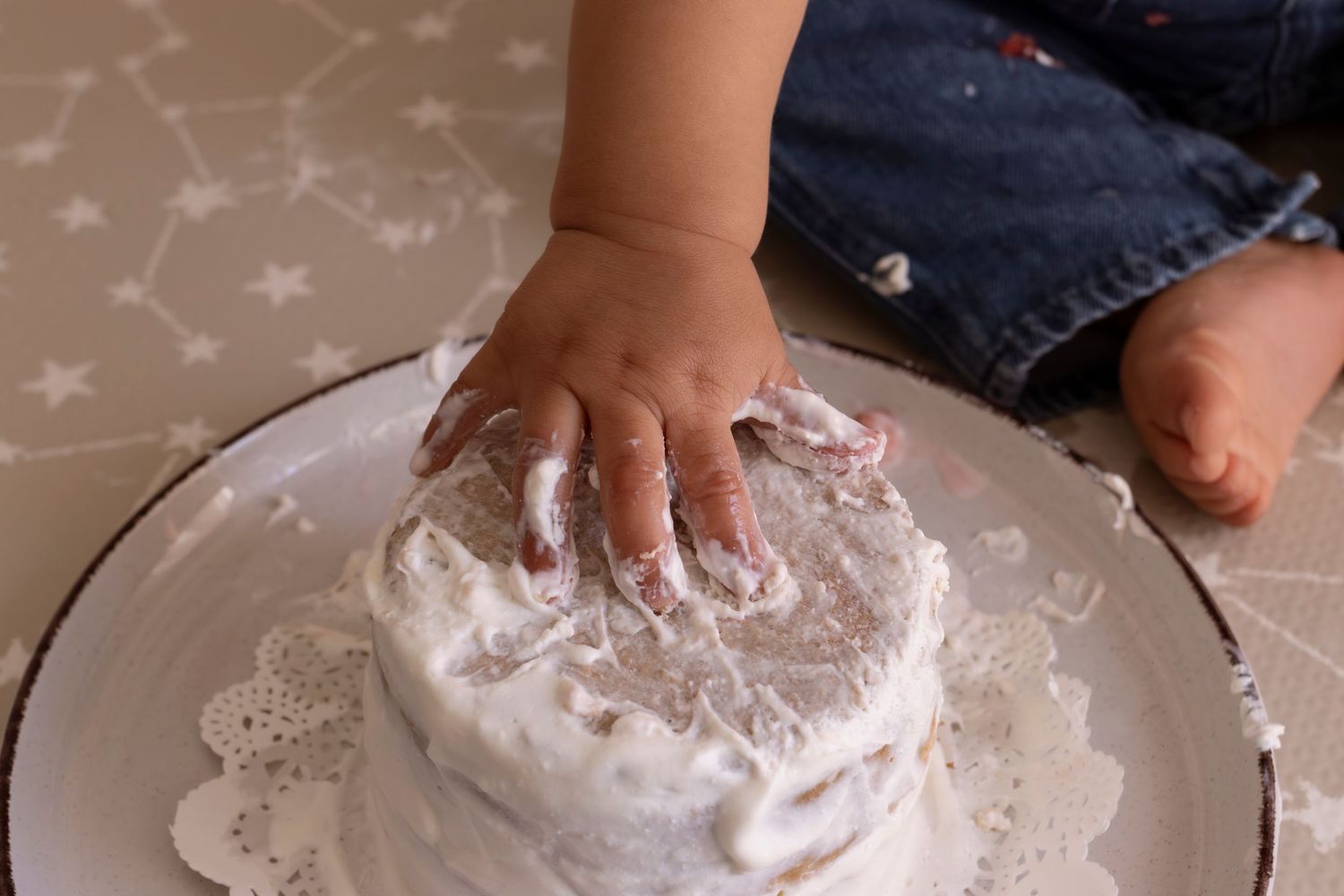 Small hands kneading and playing with white flour or powdery dough mixture on a light-colored surface.