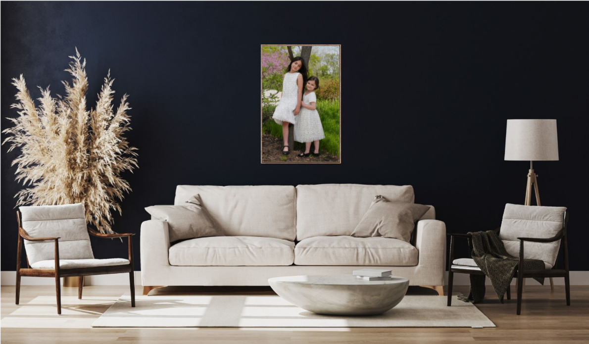 Two girls in white dresses pose for a portrait displayed as wall art in a modern dark living room.