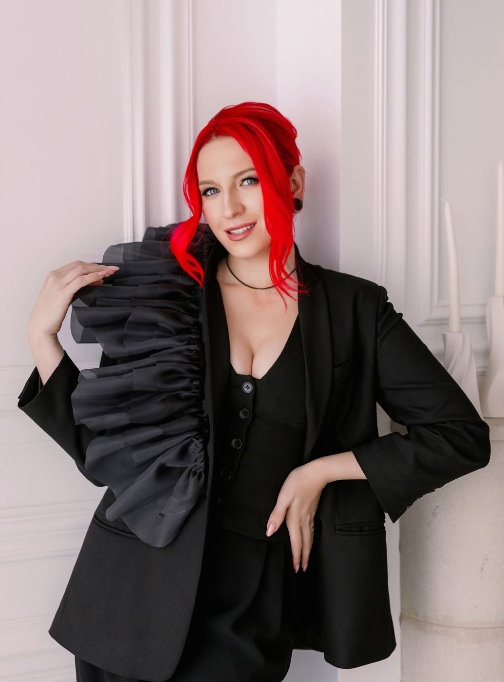 A figure in a black blazer with vibrant red hair poses elegantly against a white backdrop in a photo collage.