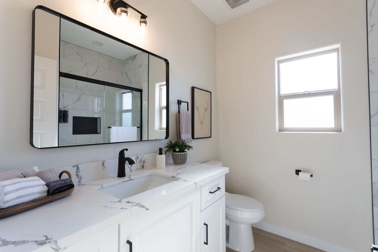 Modern white bathroom with floating vanity, round mirror, and glass shower enclosure featuring minimalist design elements.