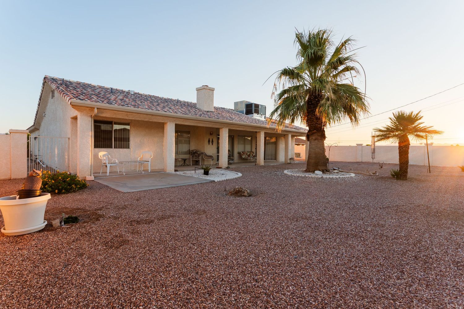 Panoramic sunset view of a desert residential neighborhood with palm trees and red rock landscaping.
