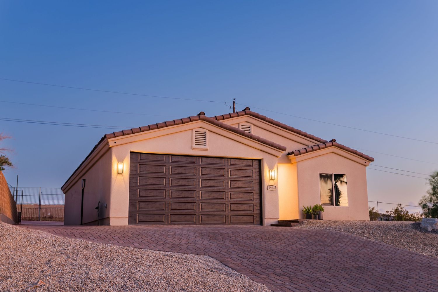 Modern residential home with stucco exterior and desert landscaping in front during golden hour sunset.