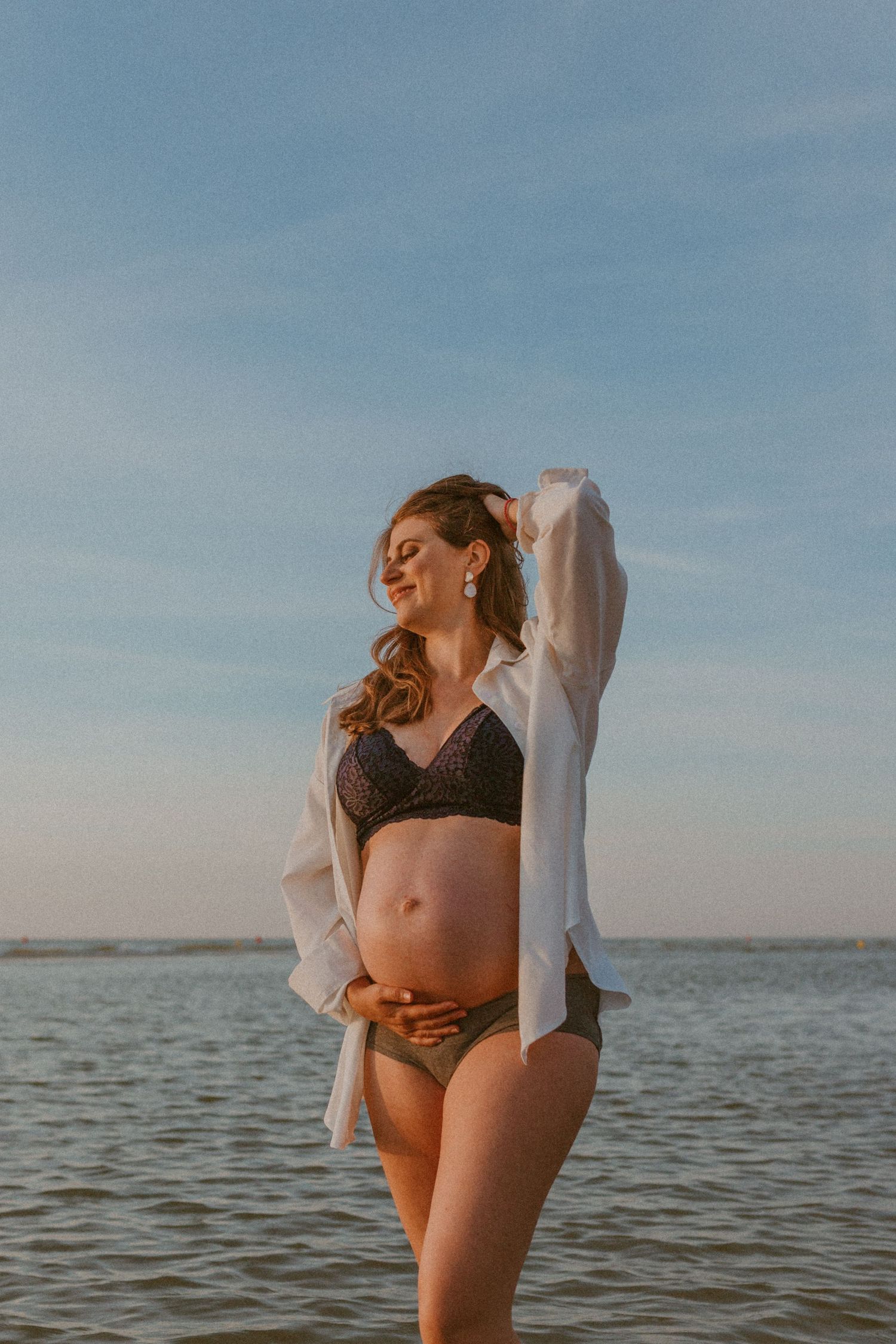Romantic couple embraces at sunset by the ocean in a series of intimate artistic photos.