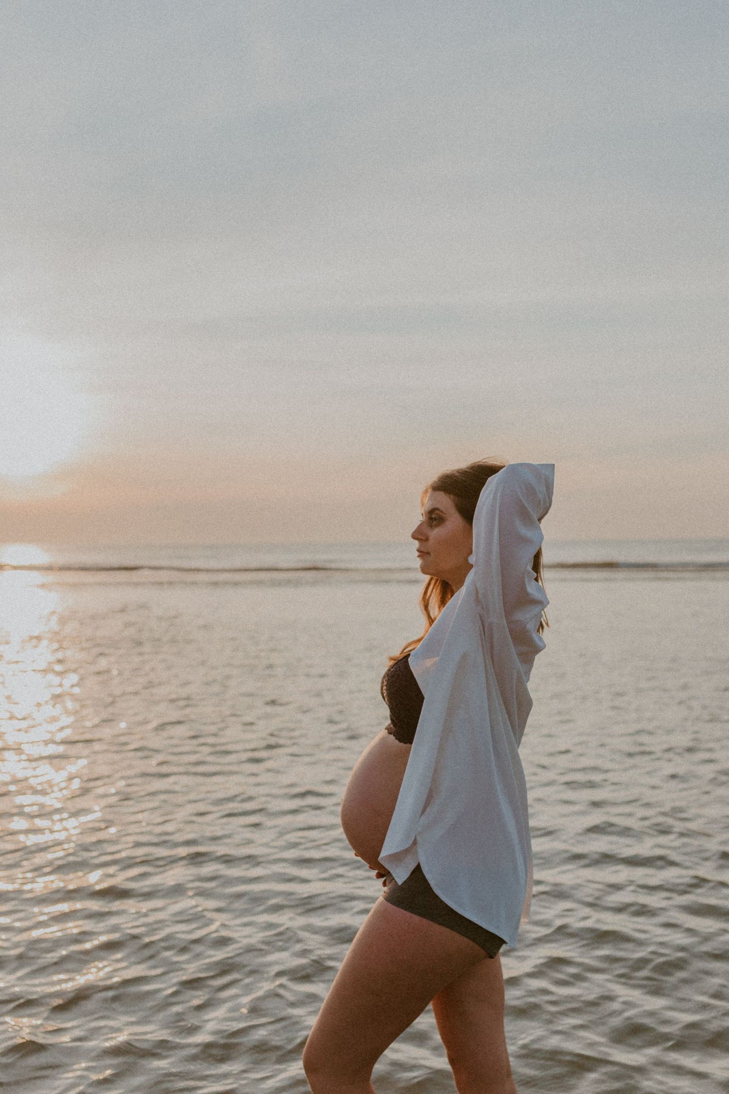 Person in white hoodie looking out at sunset over ocean in sequence of five connected photos.