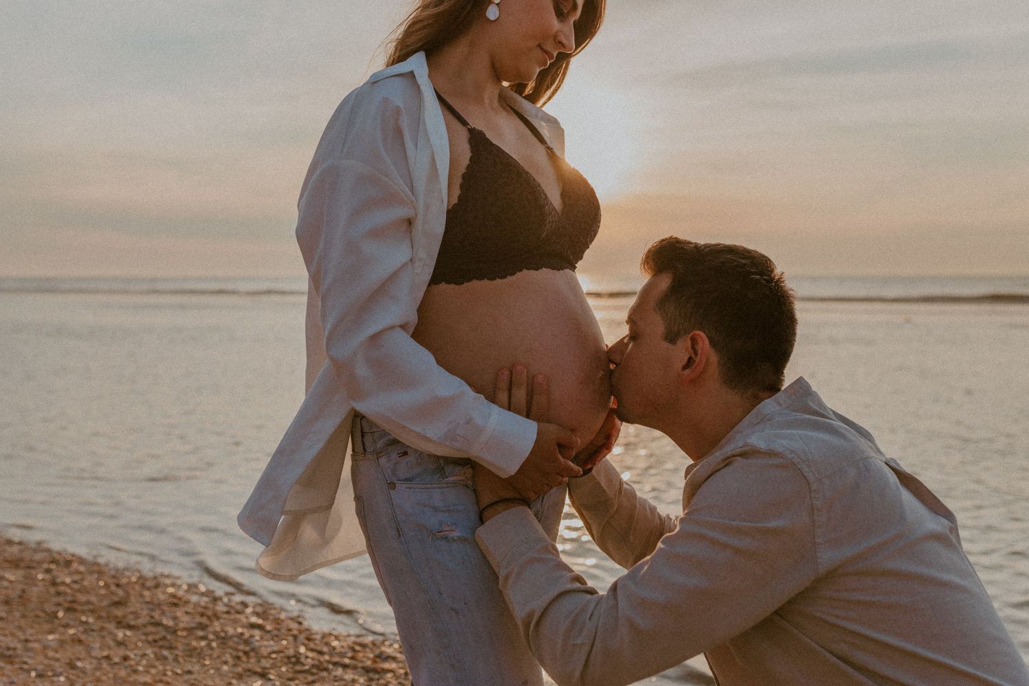 A romantic couple shares intimate moments on a beach at sunset, captured in a series of candid photographs.