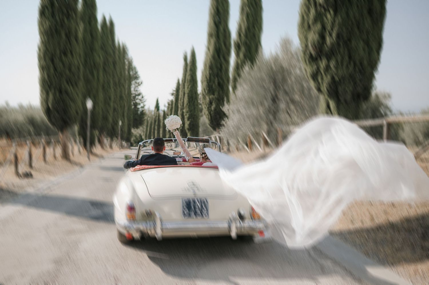Wedding couple driving through the Tuscan countryside, capturing movement and timeless Italian scenery