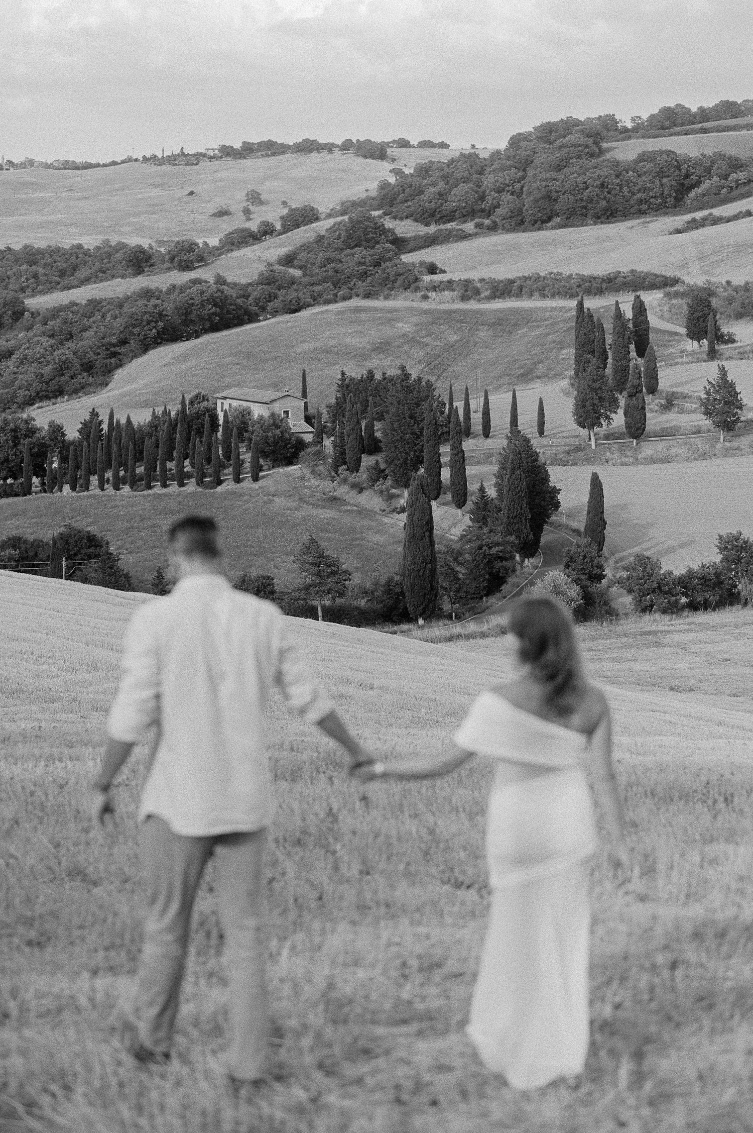 Couple walking through Tuscany countryside during engagement session