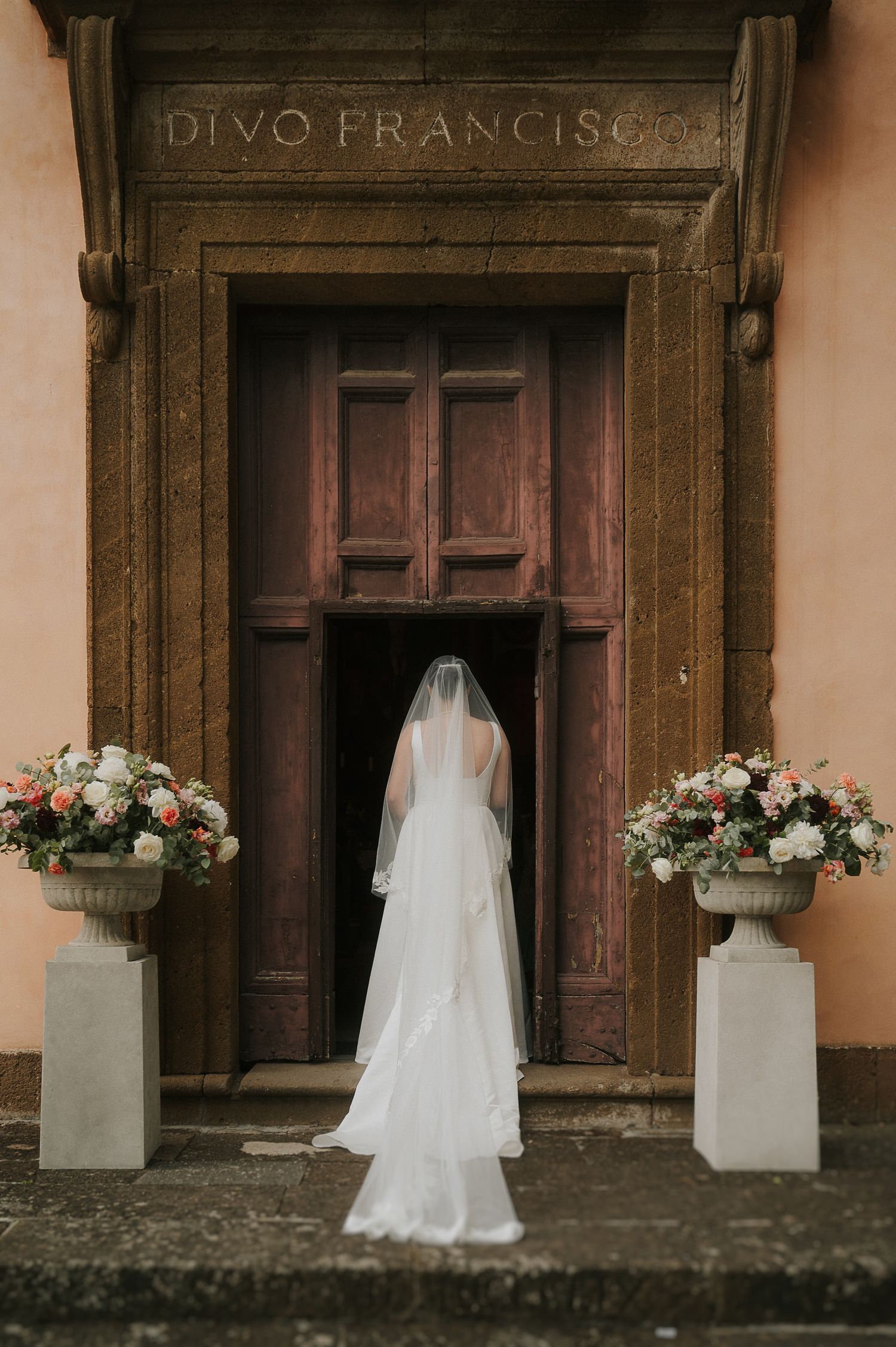 Bride standing in front of historic Italian architecture, captured in a refined and timeless editorial wedding style