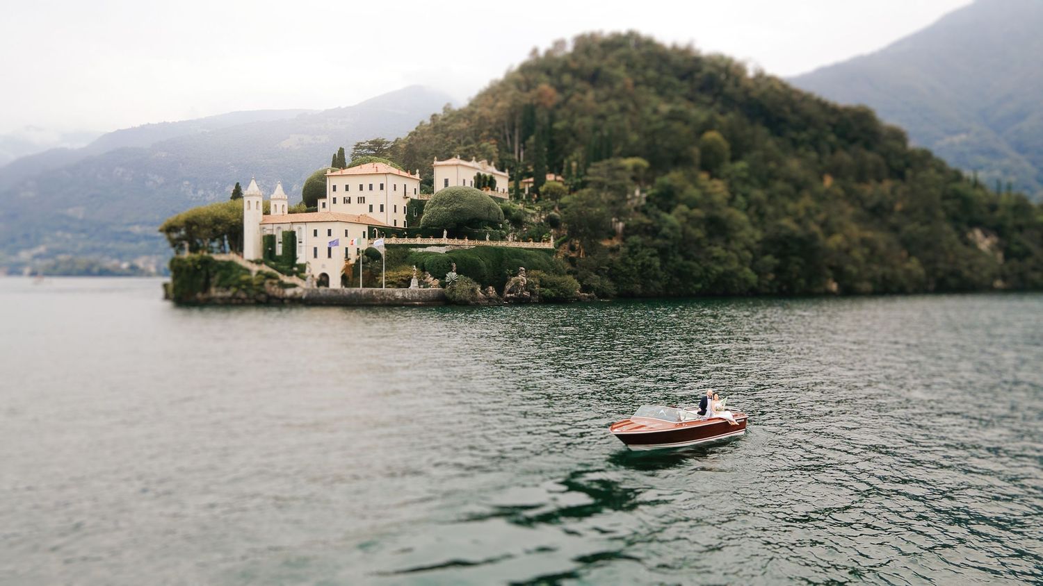 Iconic view of a luxury villa on Lake Como with a classic wooden boat on the water