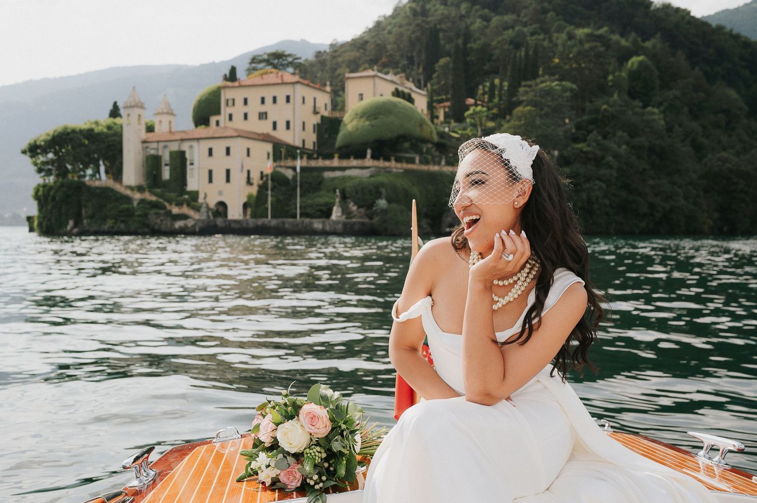 Bride enjoying a boat ride in front of Villa del Balbianello during a luxury destination wedding on Lake Como