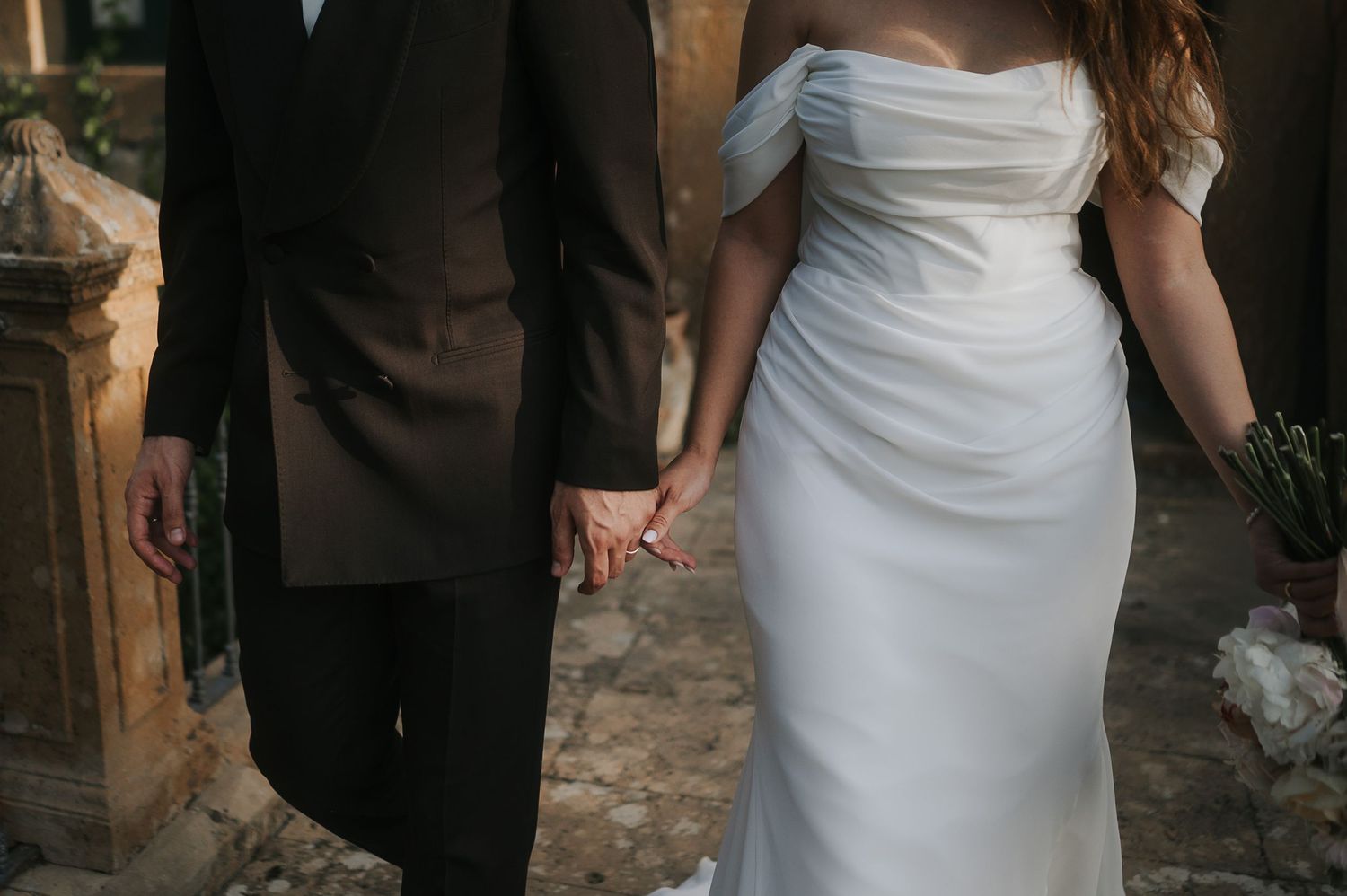 Intimate detail of the bride and groom holding hands during a luxury wedding in Sicily
