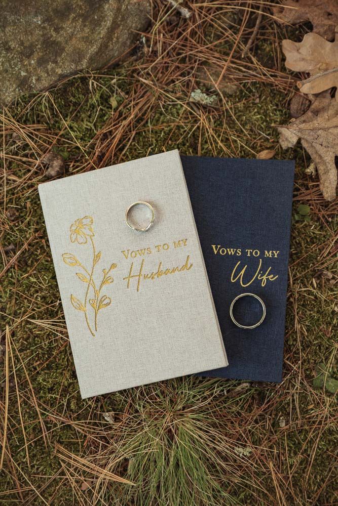 Wedding rings and vow book at wedding at June Norcross Webster Scout Reservation in Ashford, CT captured by illuminate the stars Photography