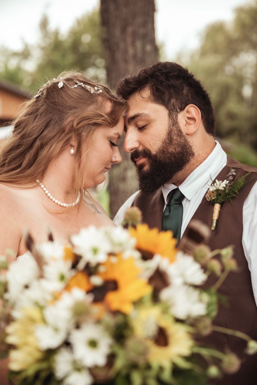Couple with flowers after their fall wedding ceremony at The Lakeside Lodge in Sydney, Maine captured by illuminate the stars Photography