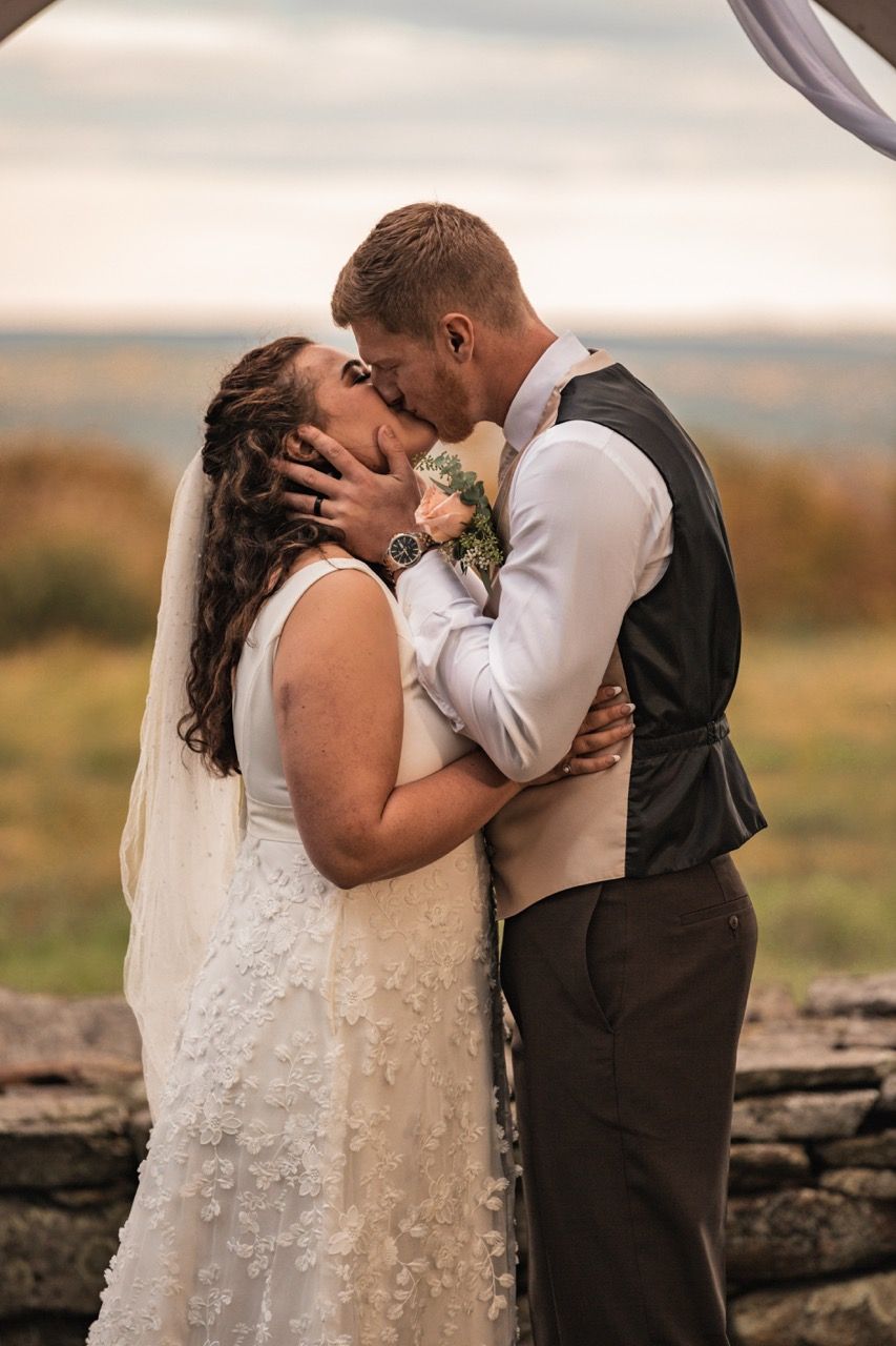 Couple's first kiss during their fall wedding at Beech Hill Barn in Pittston, Maine captured by illuminate the stars Photography