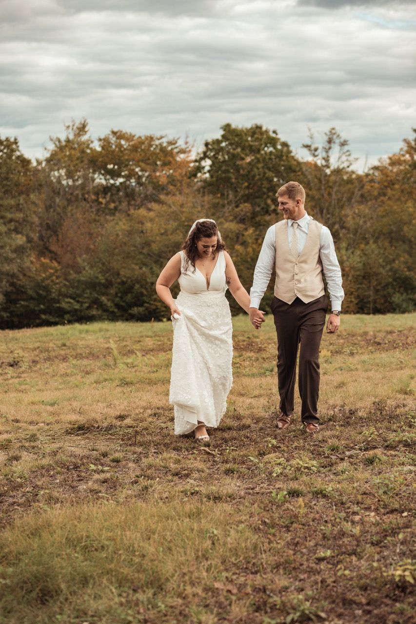 Couple walking through a field during their fall wedding at Beech Hill Barn in Pittston, Maine captured by illuminate the stars Photography
