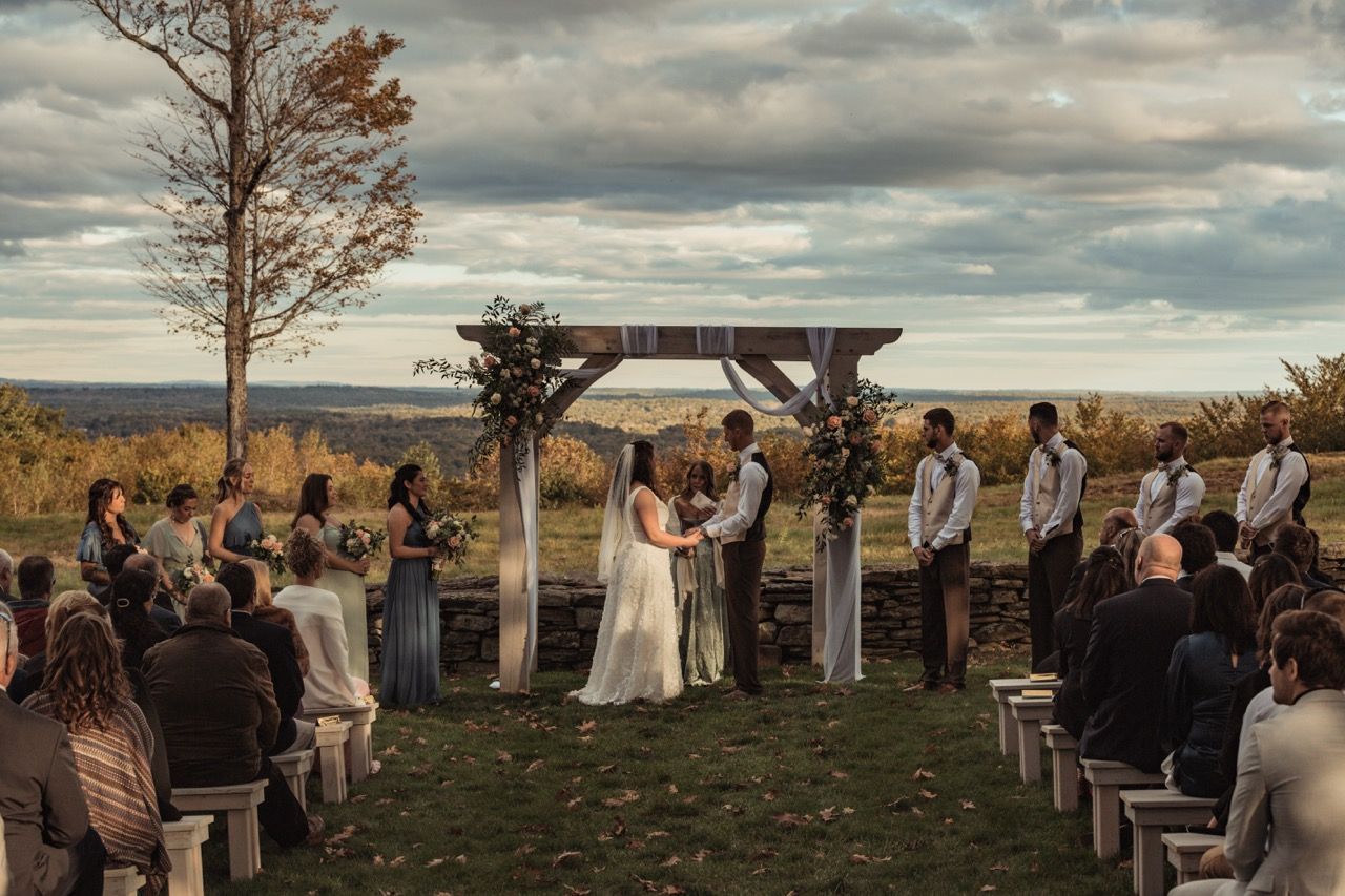 Couple exchanging vows during their fall wedding at Beech Hill Barn in Pittston, Maine captured by illuminate the stars Photography