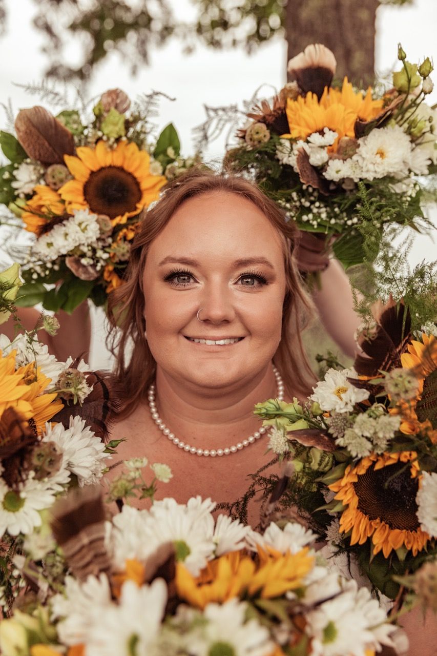 Bride surrounded by flowers during her fall wedding at The Lakeside Lodge in Sydney, Maine captured by illuminate the stars Photography