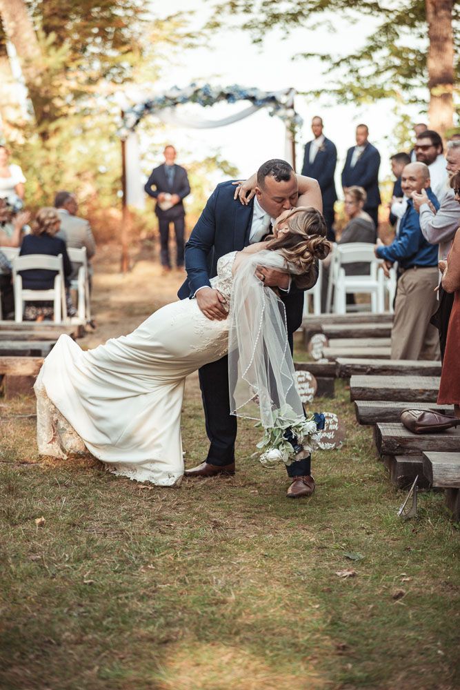 Couple kissing in aisle after fall wedding ceremony at Camp Waziyatah in Waterford, Maine captured by illuminate the stars Photography