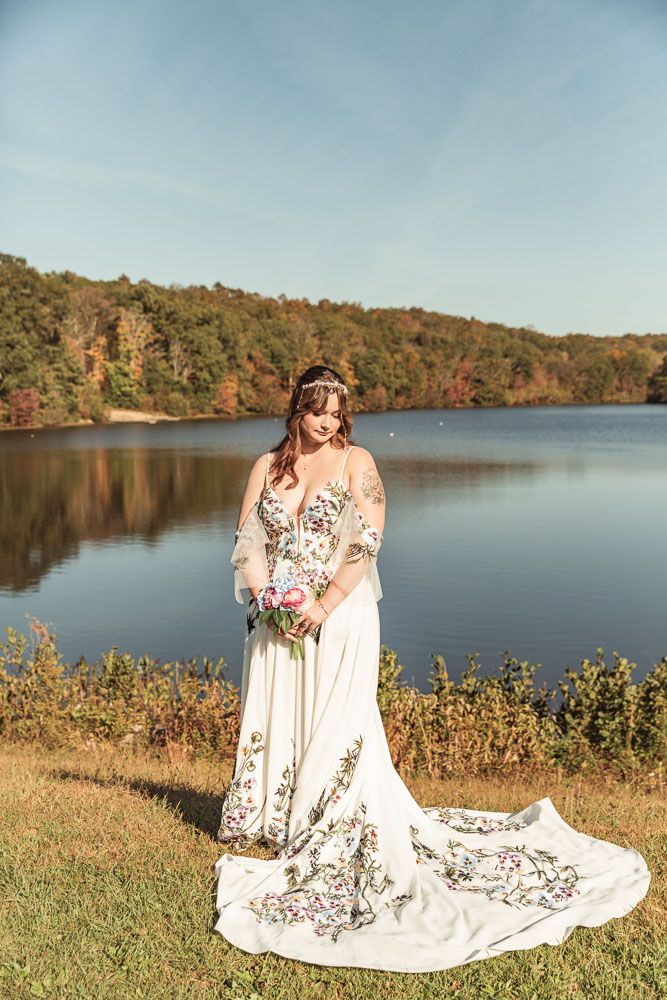Bride in her floral wedding dress during her fall wedding at June Norcross camp in Ashford, CT captured by illuminate the stars Photography