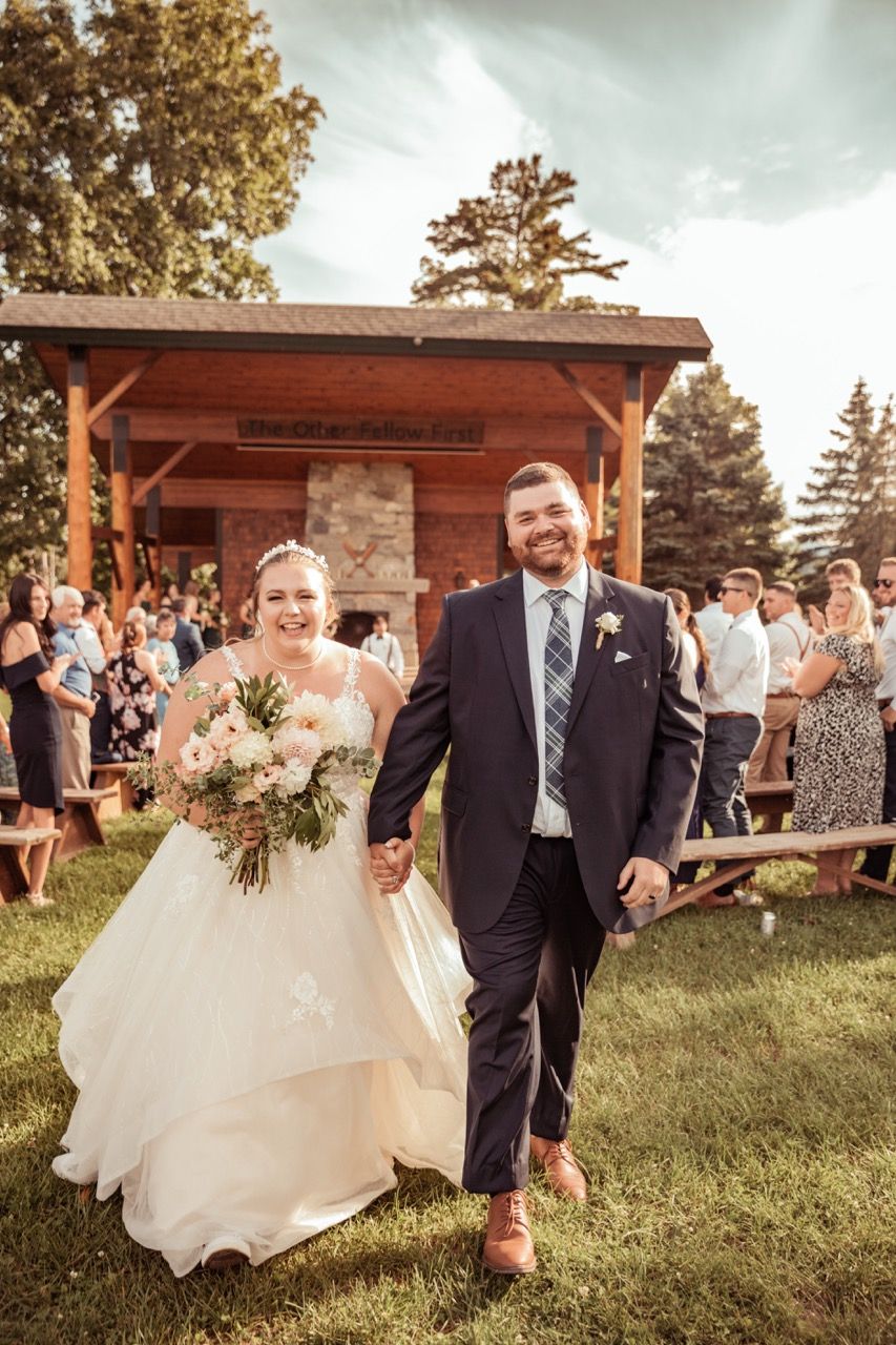 Couple holding hands exiting their fall wedding ceremony at Camp Dudley in Westport, New York captured by illuminate the stars Photography