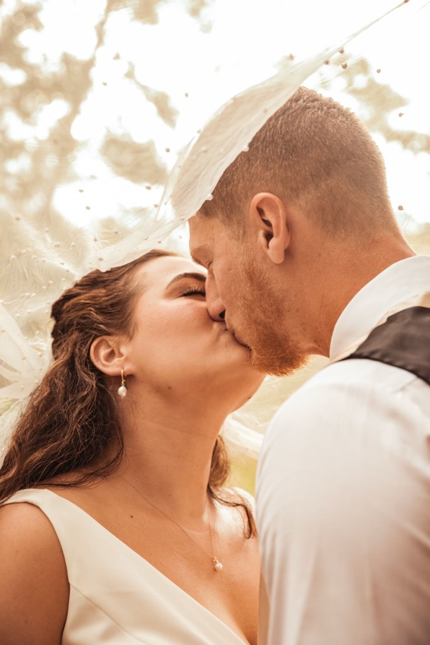 Couple kissing under bride's veil during wedding at Beech Hill Barn in Pittston, Maine captured by illuminate the stars Photography