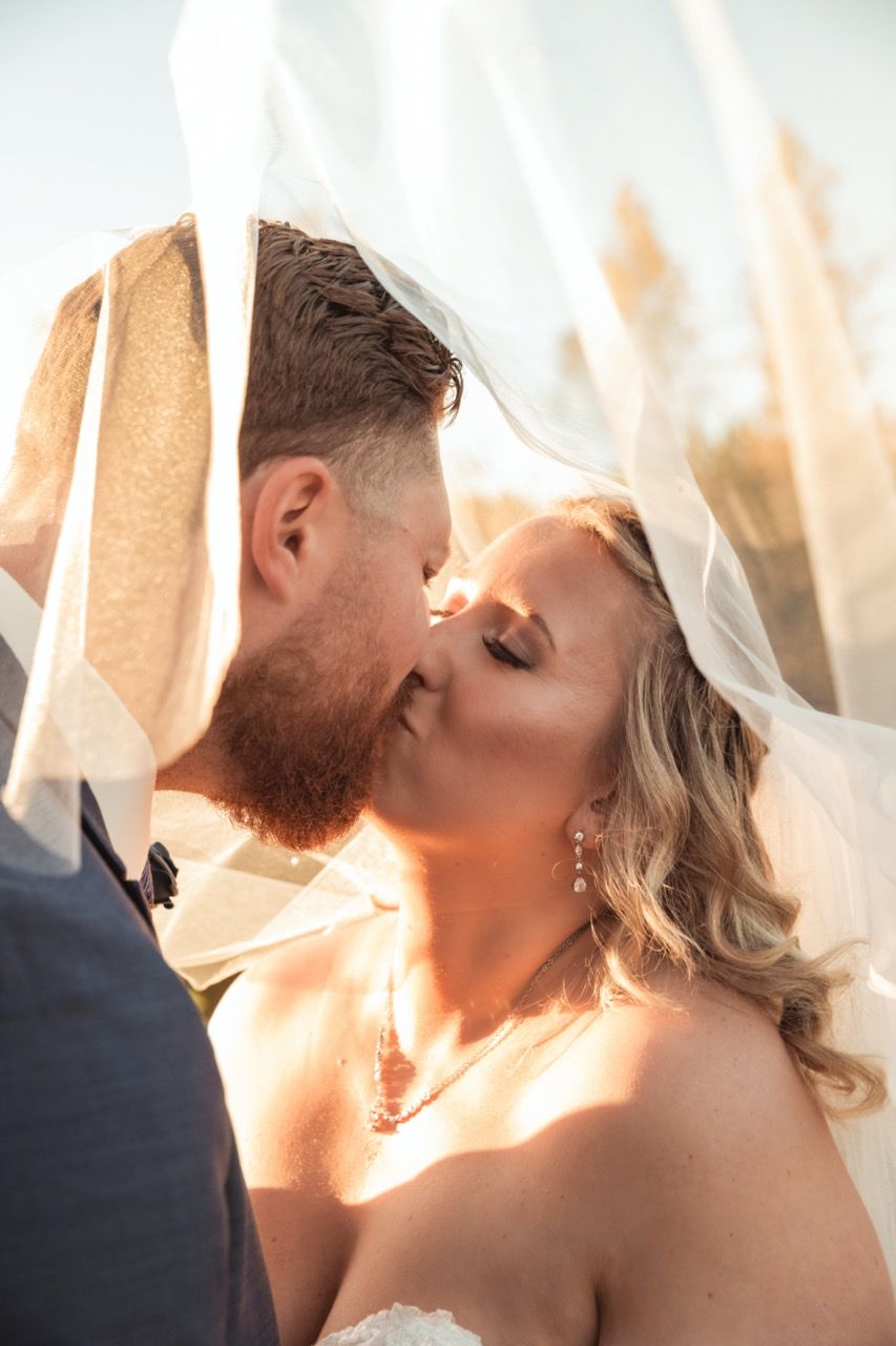 Bride and groom kissing under veil at wedding at Morgan Hill Event Center in Herman, Maine captured by illuminate the stars Photography