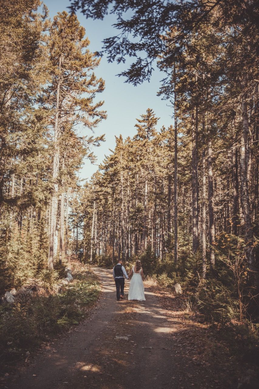Newly married couple walking in the woods after their wedding ceremony in Beaver Cove, Maine captured by illuminate the stars Photography