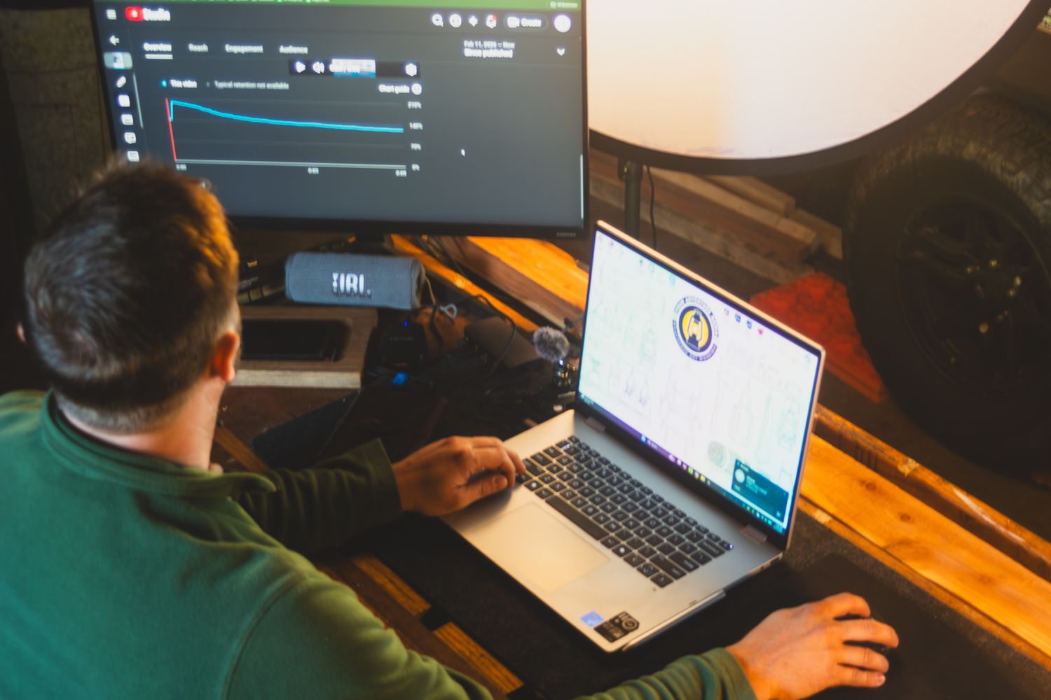 High-Res BTS Workshop Photo showing David pointing at a laptop screen with a clear YouTube Retention Graph visible.