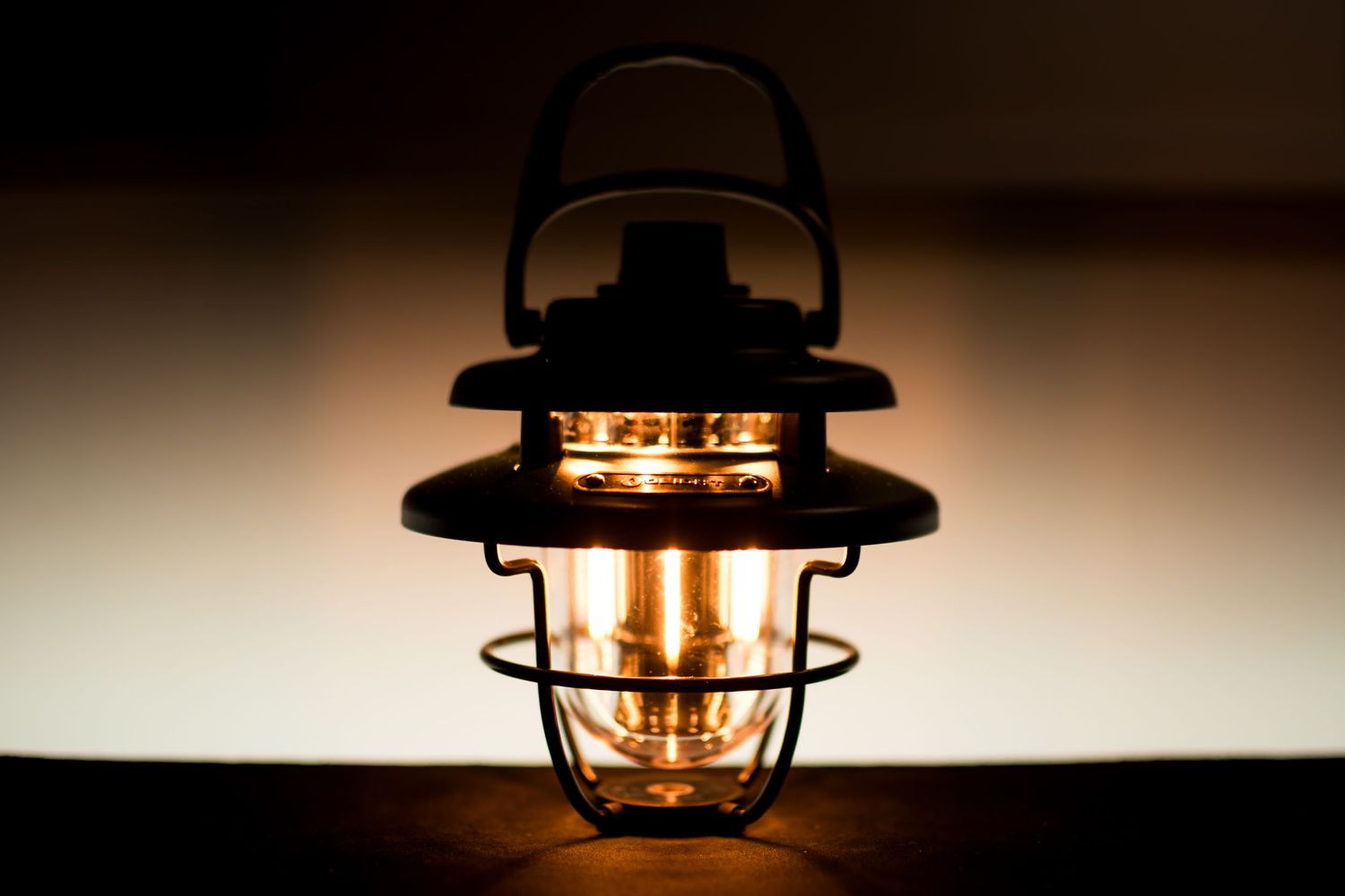 A rustic lantern with glowing orange light creates a warm and cozy atmosphere against a dark background.