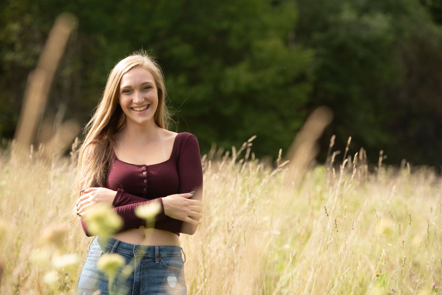 Senior portrait in a New Hampshire field during golden hour with soft, warm light.