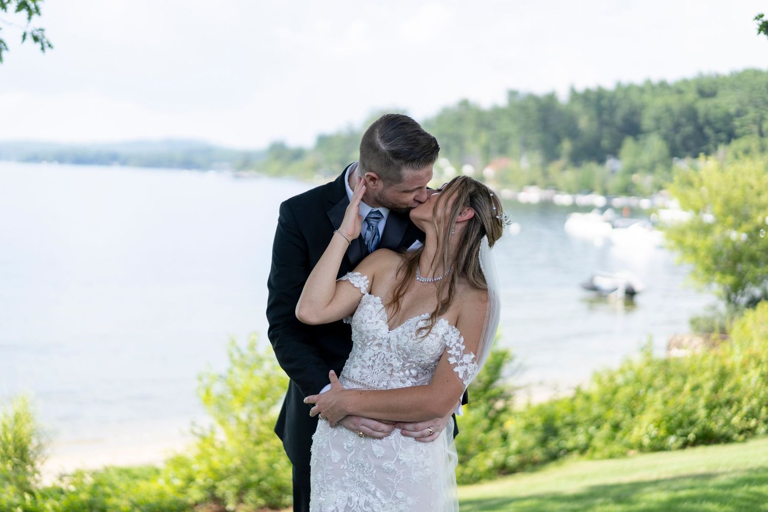Bride and groom sharing a romantic moment at a lakeside wedding.