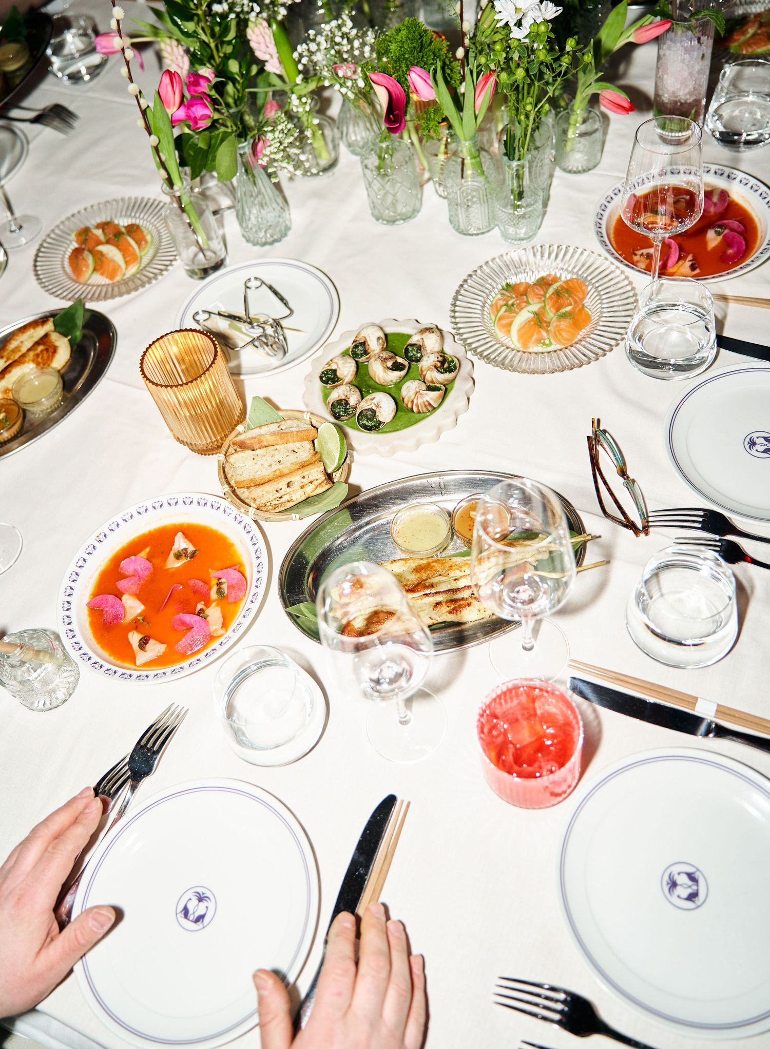 Overhead view of an elegantly set dining table with colorful dishes and floral centerpiece.