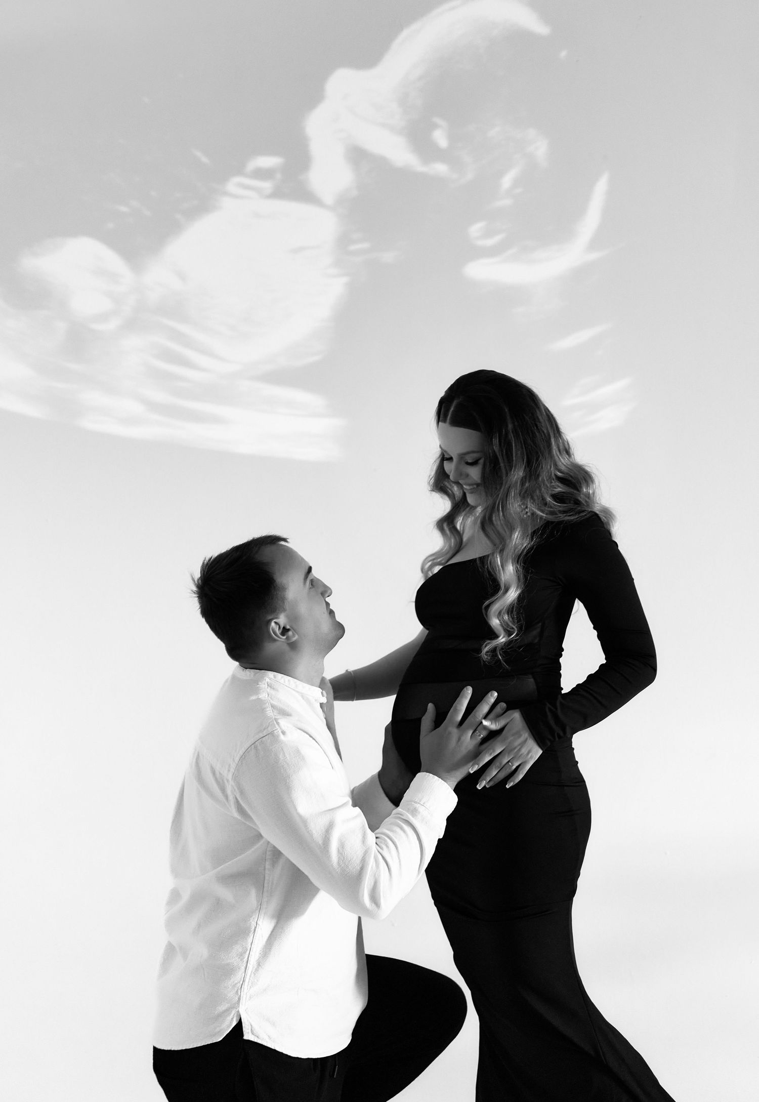 Black and white maternity photo with couple and ultrasound image overlay.