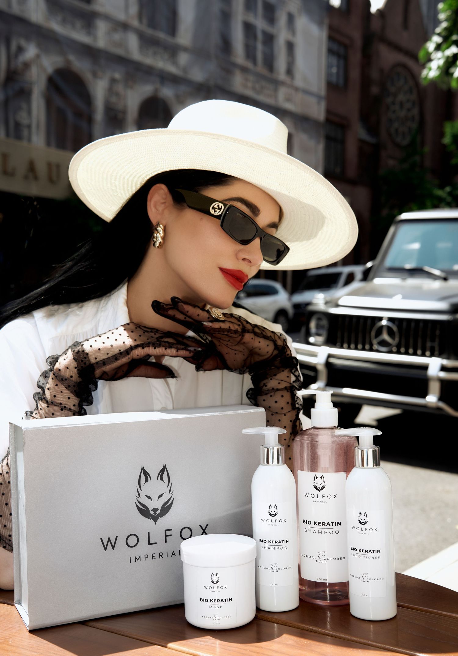 Elegant woman in white hat displays Wolfox Imperial bio keratin haircare product set.
