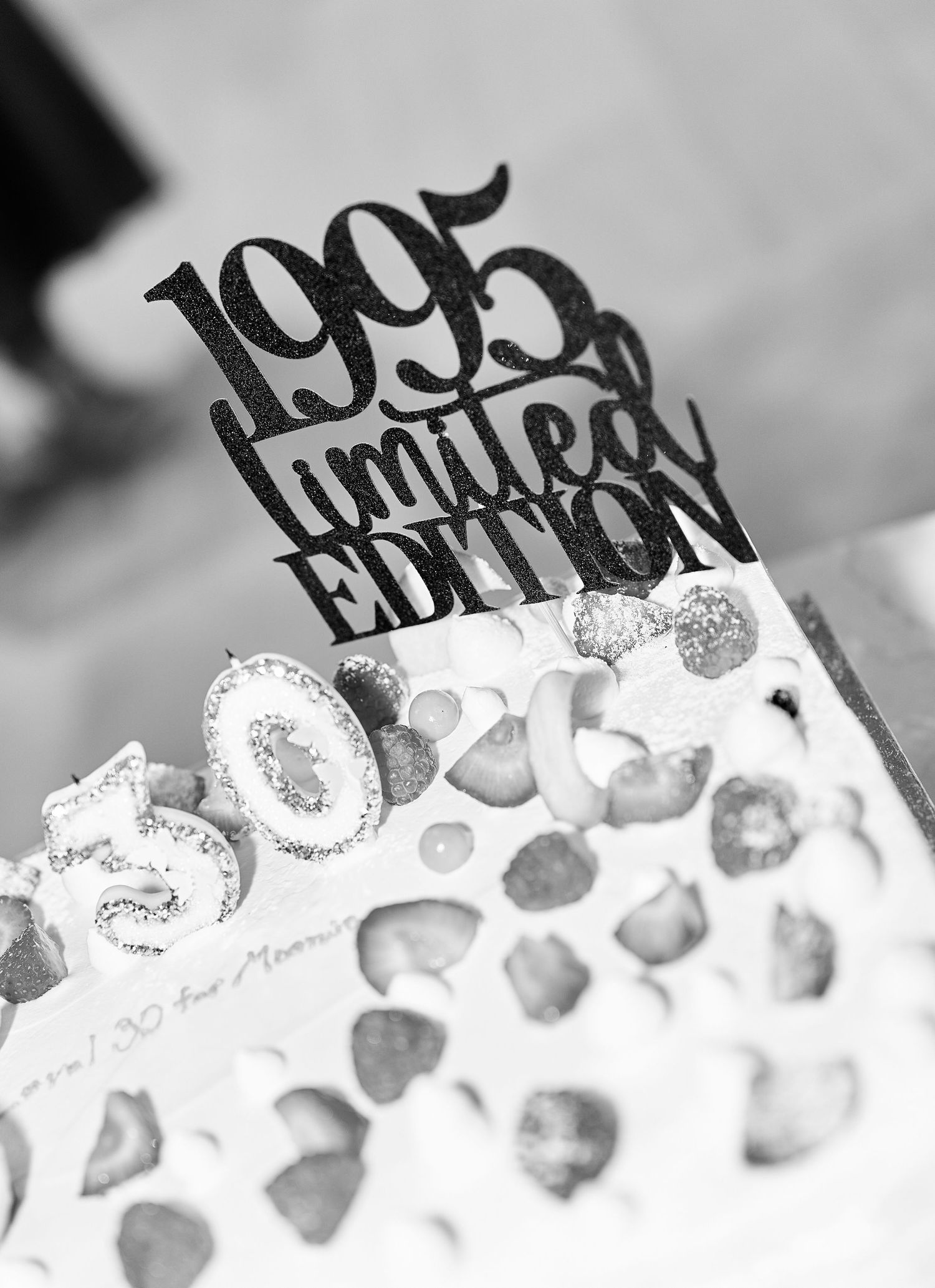 1995 Limited Edition birthday cake topper in black glitter on decorated cake.