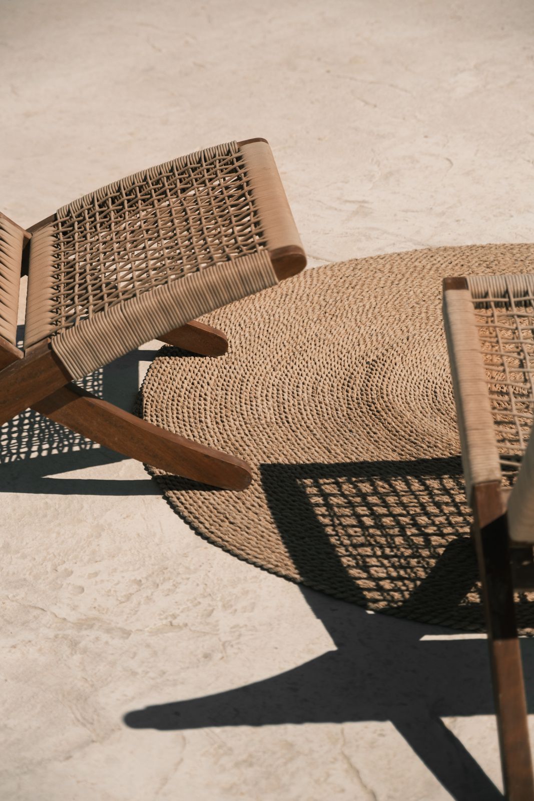 Woven rope hammock casting geometric shadows on a light concrete surface in sunlight. Interior Photography