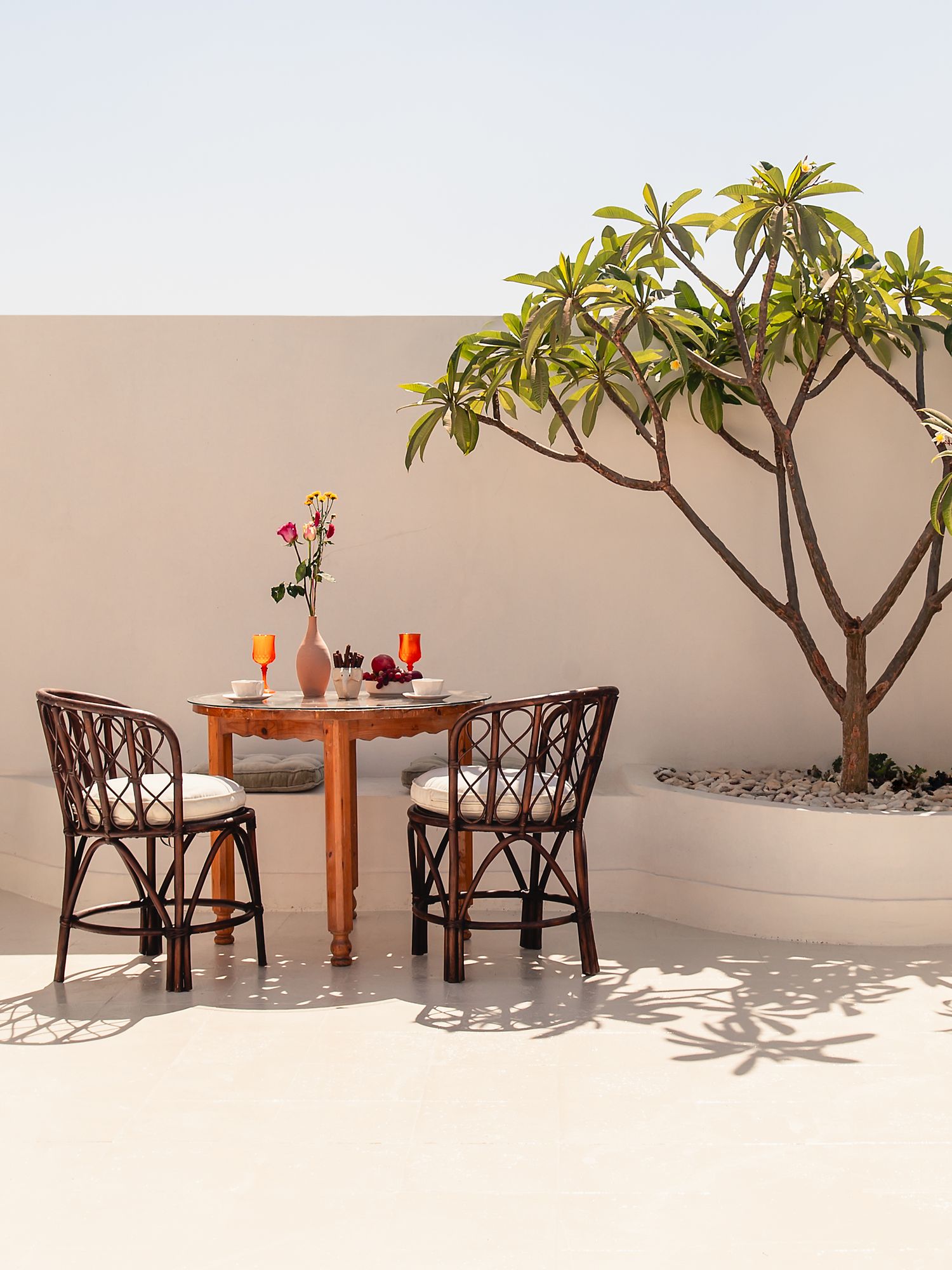 Outdoor dining setup with wooden chairs and table under tropical plants. Interior Photography