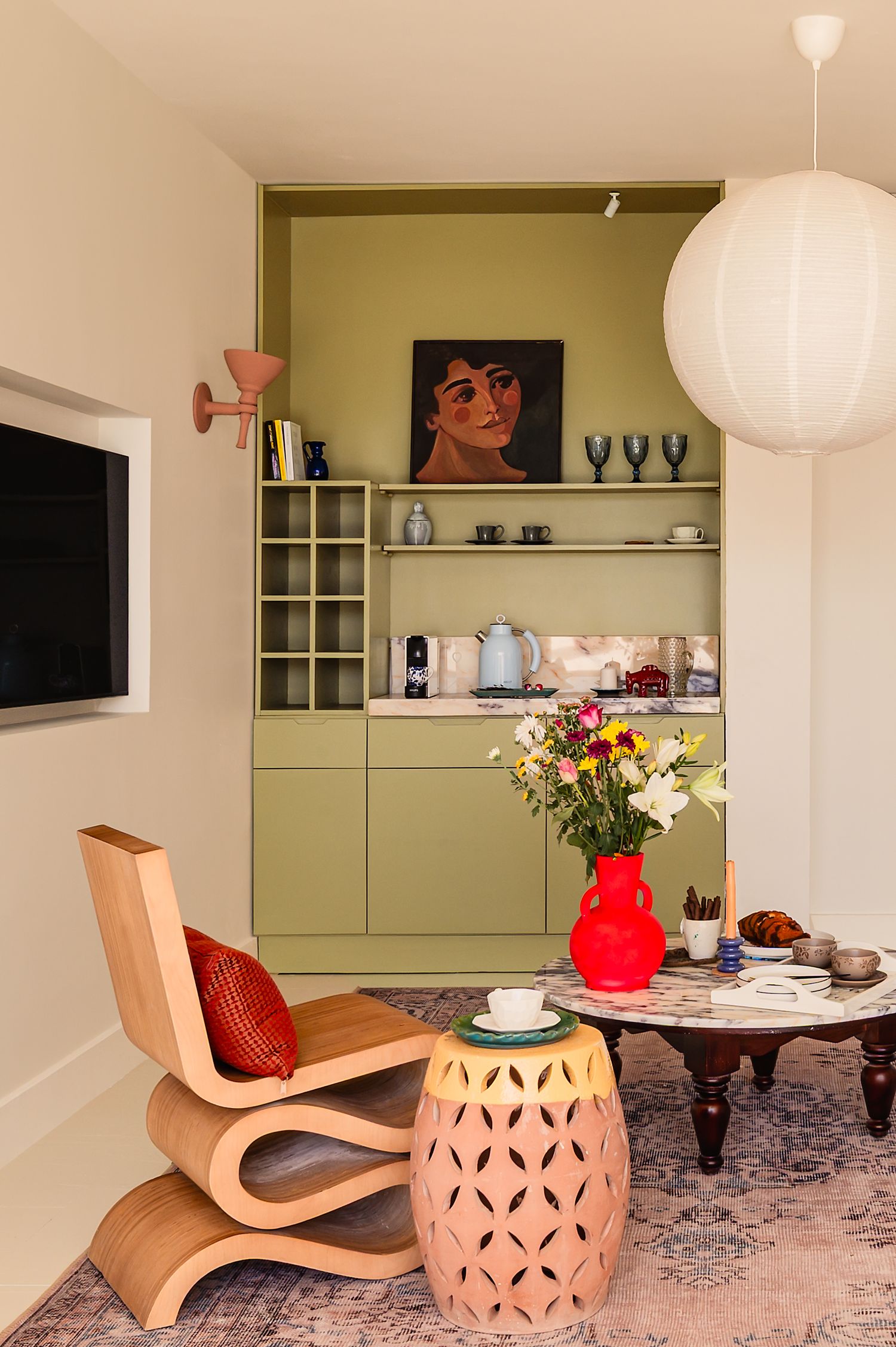 Modern living room corner with green built-in shelving, bentwood chair, and decorative paper lantern pendant light. Interior Photography