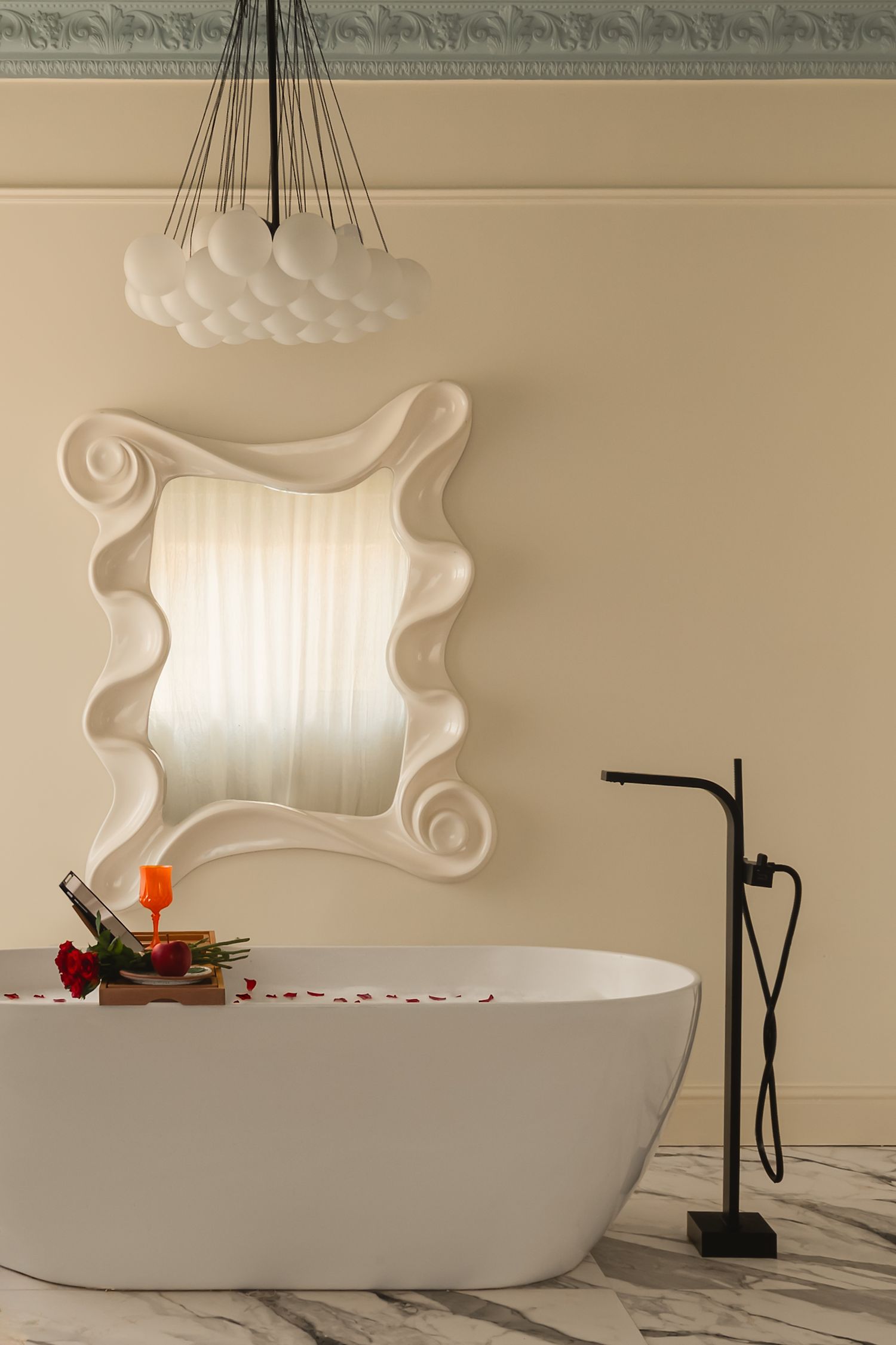 Luxurious bathroom with freestanding white bathtub and sculptural ceiling light fixture. Interior Photography