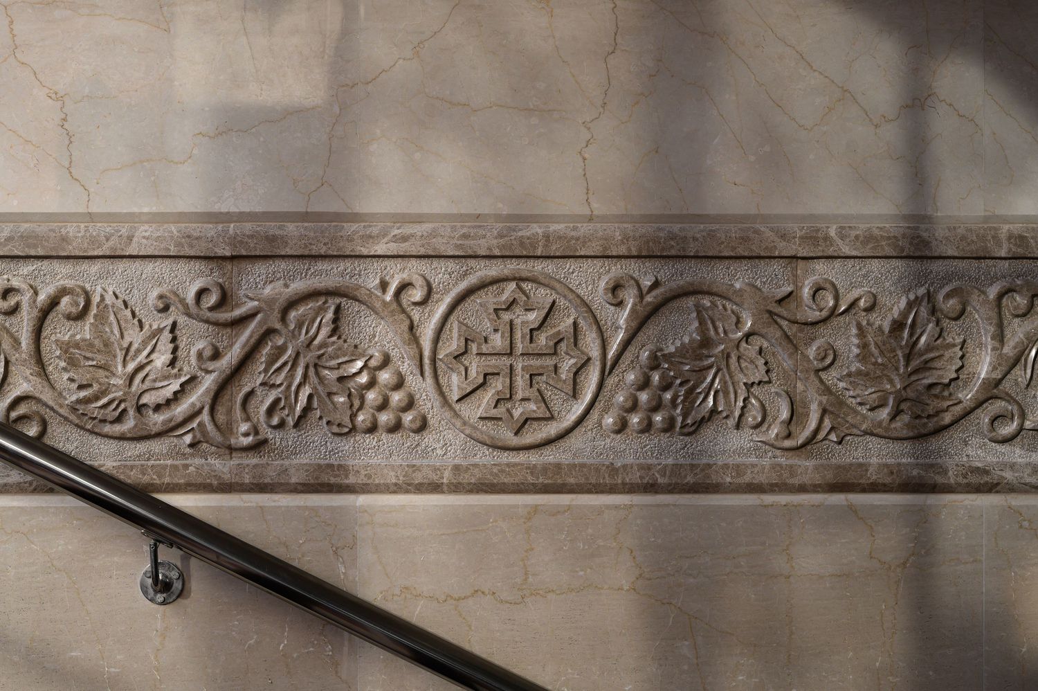 Decorative carved stone frieze with intricate patterns and motifs along a wall. Interior Photography