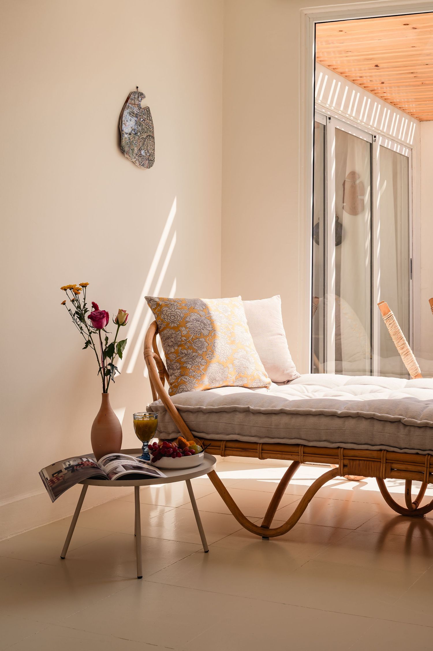 Cozy reading nook with vintage rattan lounger, small side table, and fresh flowers. Interior Photography